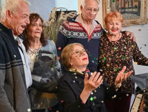 קבוצת קשישים שמחים חוגגים עם קונפטי בבית גיל הזהב תל אביב, דיור מוגן יוקרתי. - סביבה תוססת ומפוארת המציעה שירותים תרבותיים, חברתיים ורפואיים לקשישים בלב תל אביב.