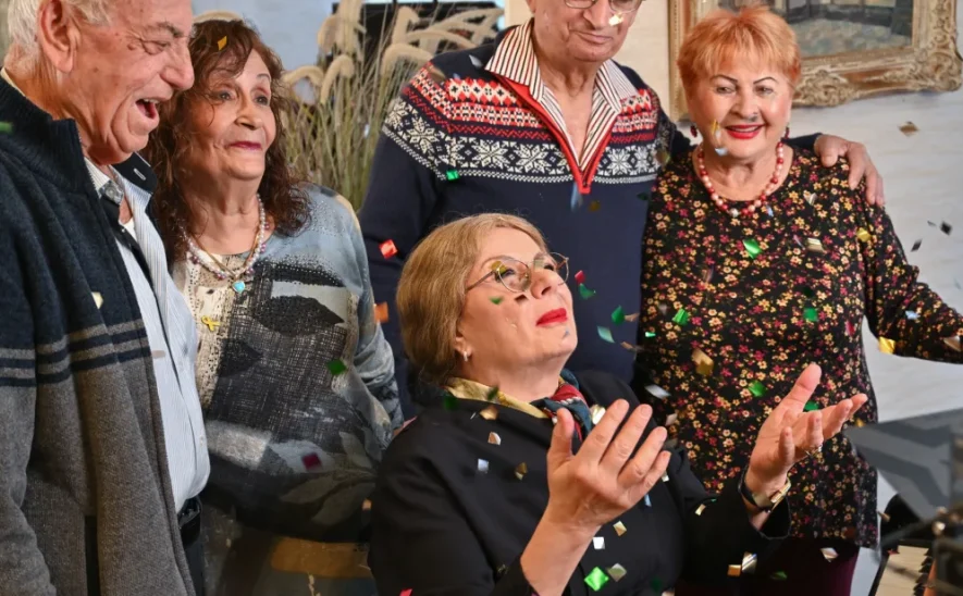 קבוצת קשישים שמחים חוגגים עם קונפטי בבית גיל הזהב תל אביב, דיור מוגן יוקרתי. - סביבה תוססת ומפוארת המציעה שירותים תרבותיים, חברתיים ורפואיים לקשישים בלב תל אביב.